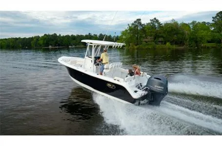 Slide: The Image of 2022 Sea Hunt Ultra 229 boat cruising on a serene lake with lush green surroundings. - 25