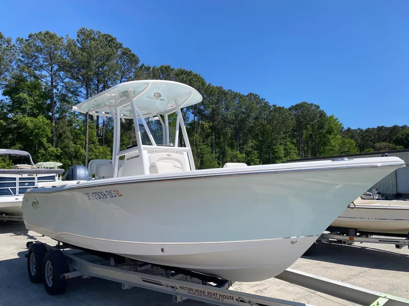 Slide: The Image of 2022 Sea Hunt Ultra 229 boat on trailer, surrounded by trees under clear blue sky. - 27