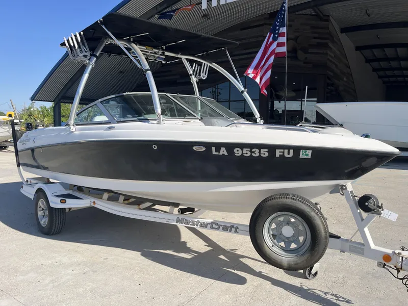 Slide: The Image of 2006 MasterCraft MariStar 210 boat on trailer with American flag, parked outdoors. - 10