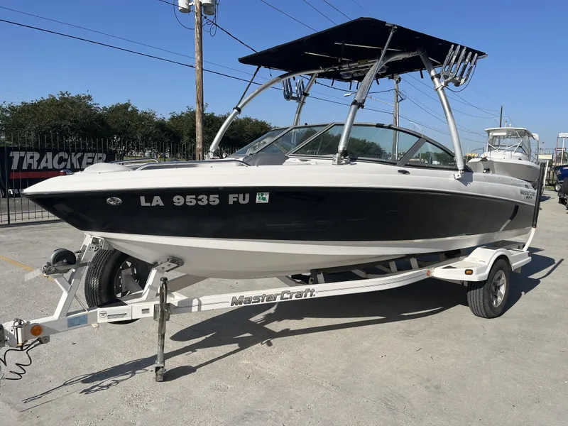 Slide: The Image of 2006 MasterCraft MariStar 210 boat on trailer, parked outdoors under clear sky. - 12