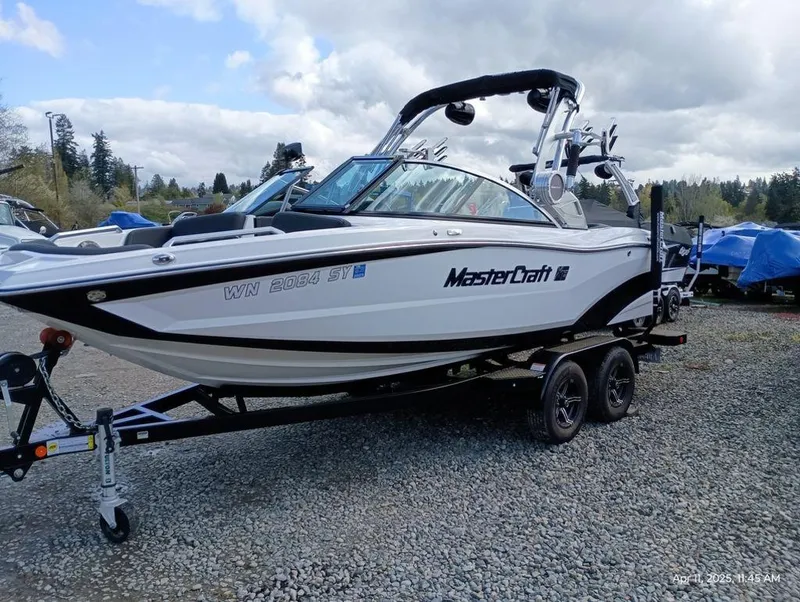Slide: The Image of 2021 MasterCraft XT20 boat on trailer, parked outdoors on gravel. - 1
