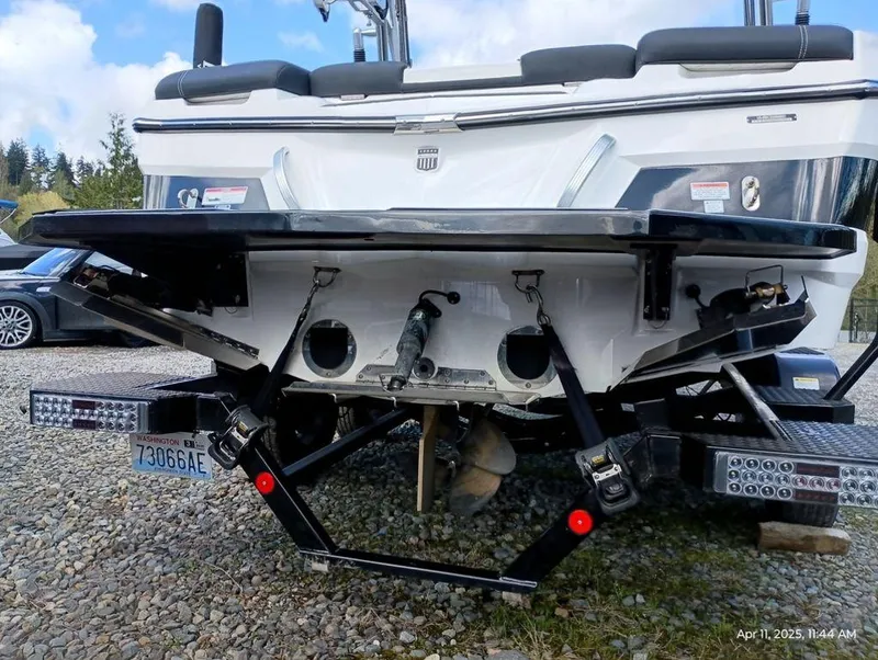 Slide: The Image of 2021 MasterCraft XT20 boat rear view with trailer, parked on gravel. - 14