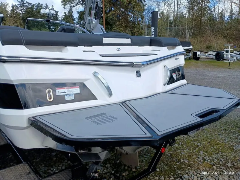 Slide: The Image of 2021 MasterCraft XT20 boat rear view with swim platform, parked outdoors. - 3