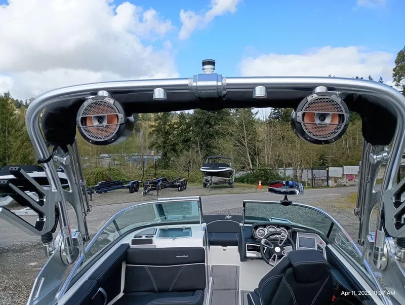 Slide: The Image of 2021 MasterCraft XT20 boat interior with speakers, steering wheel, and dashboard, under a blue sky. - 6