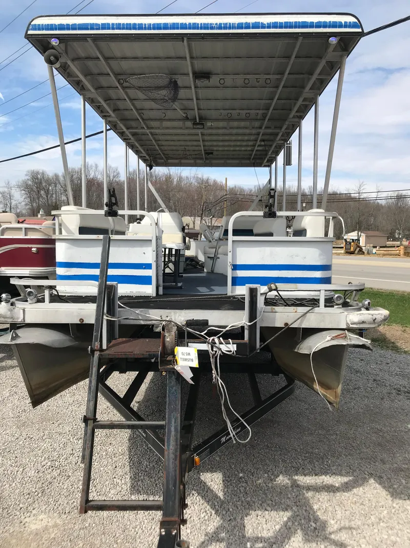 Slide: The Image of 1995 Manitou 24 Spirit pontoon boat with canopy, docked on gravel. - 2