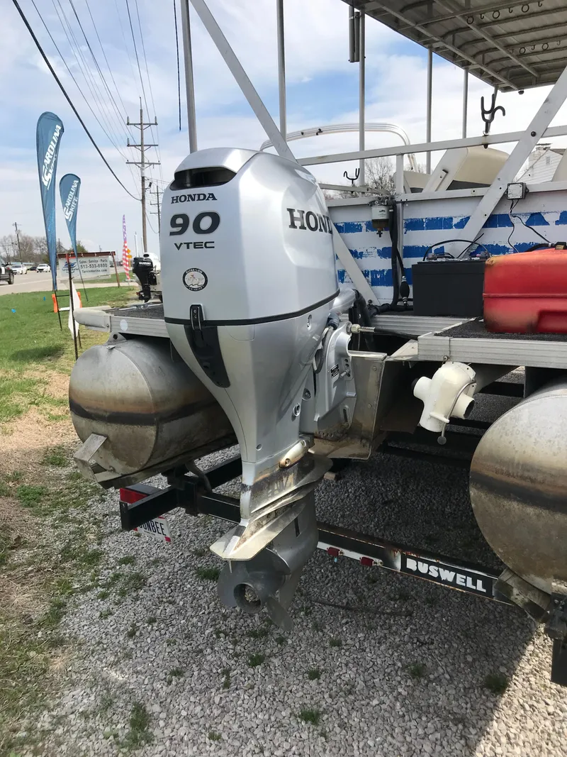 Slide: The Image of 1995 Manitou 24 Spirit pontoon boat with Honda 90 VTEC outboard motor, parked on gravel. - 6