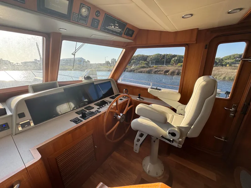 Slide: The Image of 2023 Outer Reef Yachts 720 Azure cockpit with helm, wooden accents, and panoramic windows. - 23