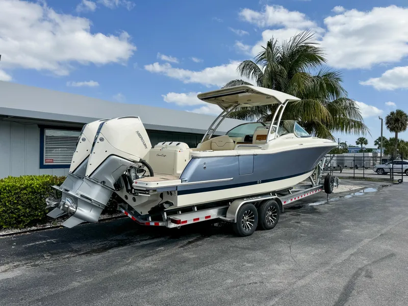 Slide: The Image of 2025 Chris-Craft Calypso 28 boat on trailer, parked outdoors under a clear sky. - 1