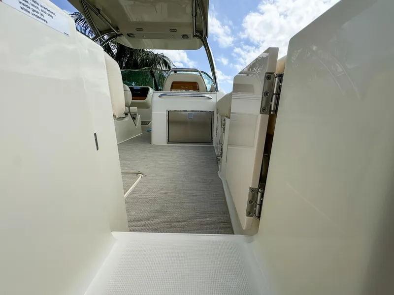 Slide: The Image of 2025 Chris-Craft Calypso 28 interior view with open door, showcasing seating and storage. - 13