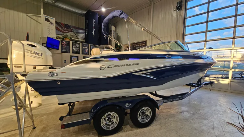Slide: The Image of 2020 Crownline Eclipse E215 XS boat displayed indoors on a trailer. - 1