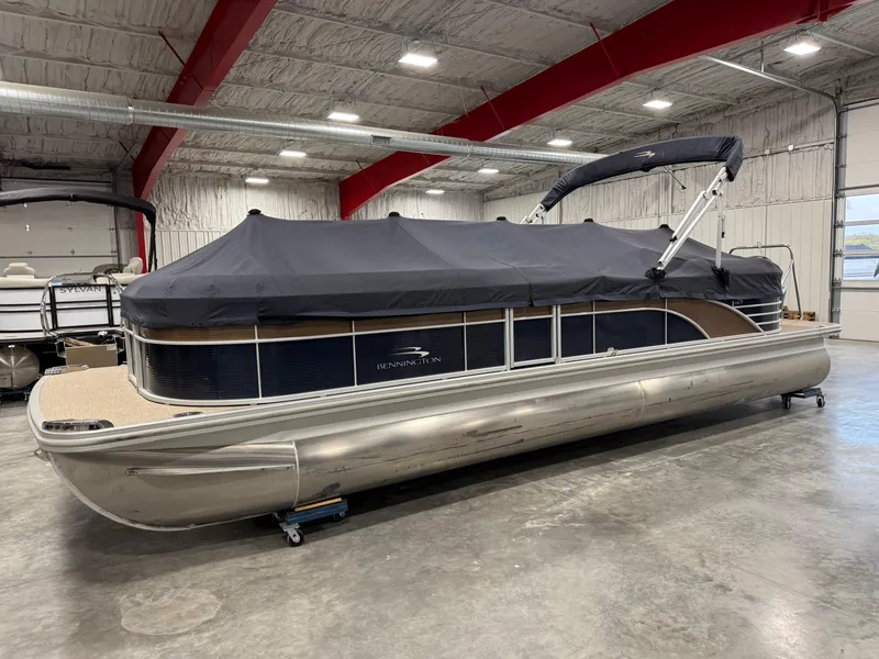 Slide: The Image of 2018 Bennington G 25 pontoon boat with cover in a warehouse setting. - 12