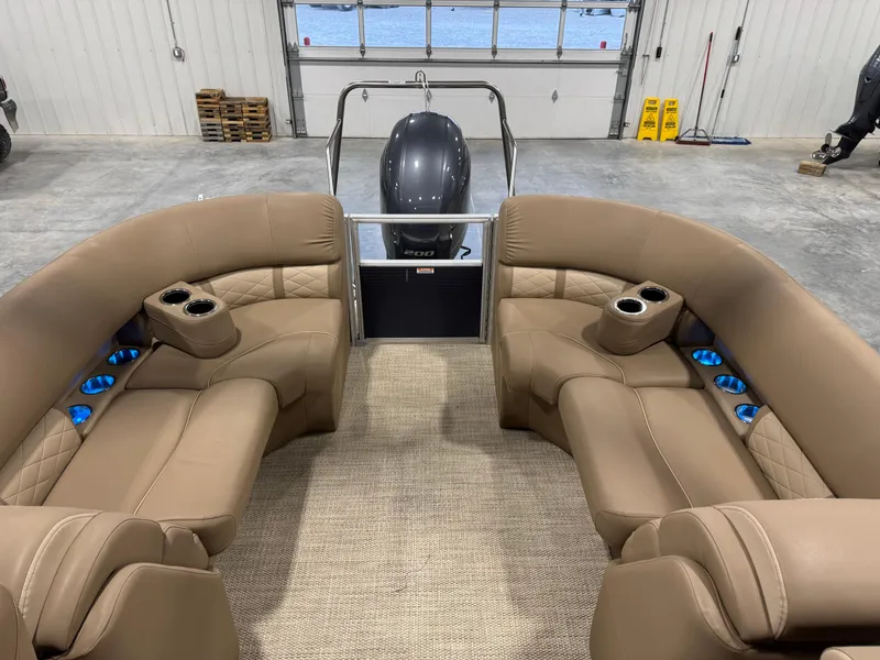 Slide: The Image of 2018 Bennington G 25 boat interior with tan seating and cup holders in a garage. - 7