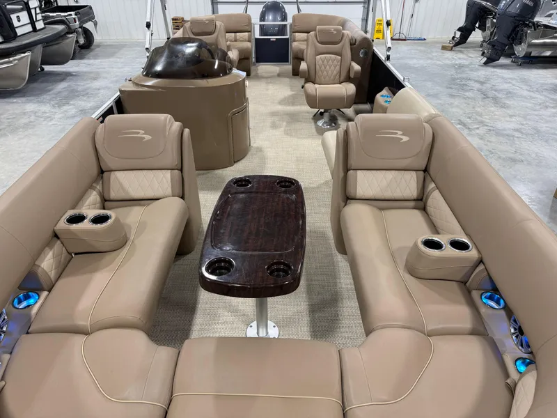 Slide: The Image of 2018 Bennington G 25 pontoon boat interior with beige seating and central table. - 9