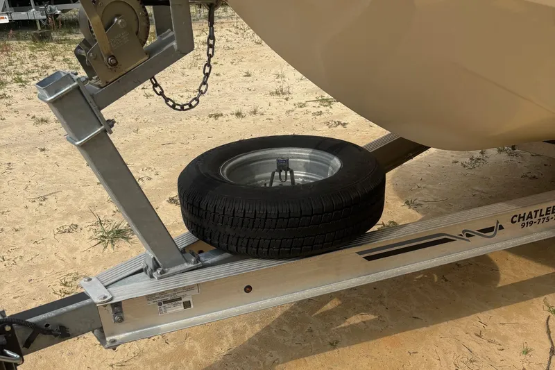 Slide: The Image of Trailer with spare tire for 2021 Carolina Skiff 19 LS boat on sandy ground. - 12