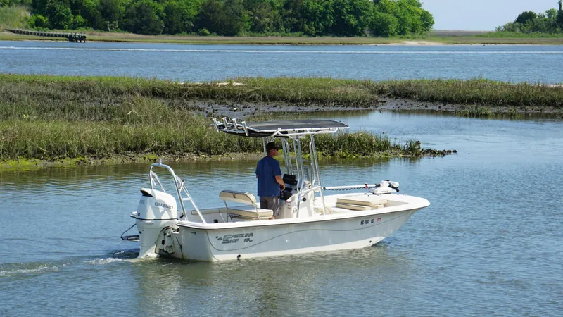 Slide: The Image of 2021 Carolina Skiff 19 LS boat navigating through calm waters near marshland. - 2