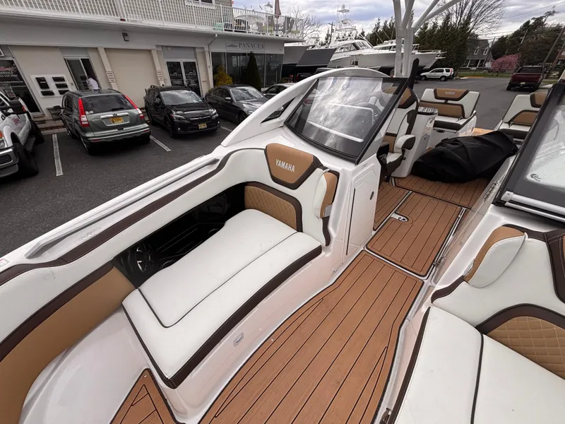 Slide: The Image of 2021 Yamaha Boats 275 SD with luxurious seating and sleek design in a marina setting. - 22