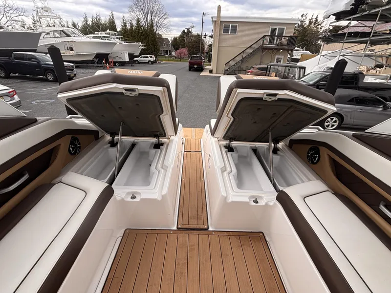 Slide: The Image of 2021 Yamaha Boats 275 SD with open storage compartments on a wooden deck. - 7