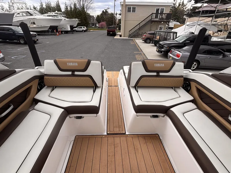 Slide: The Image of 2021 Yamaha Boats 275 SD interior with luxurious seating and wood accents in a marina setting. - 8