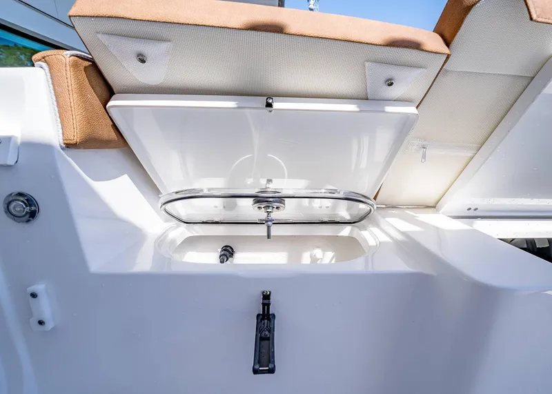 Slide: The Image of 2025 Sea Hunt Ultra 265 SE boat with open storage compartment and cushioned seating. - 11