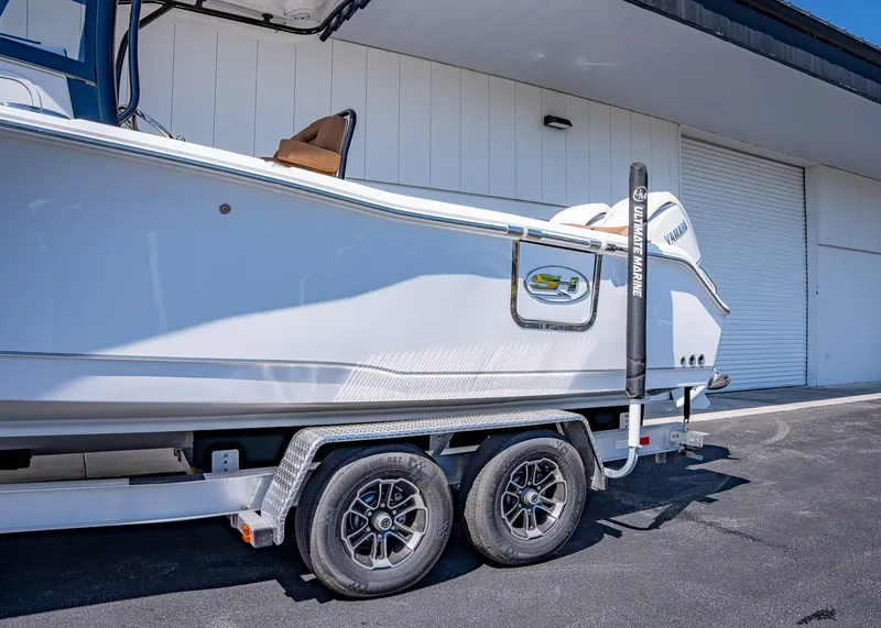 Slide: The Image of 2025 Sea Hunt Ultra 265 SE boat on trailer, parked near a white building. - 3