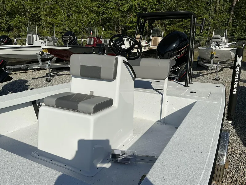 Slide: The Image of 2025 Xpress Skiff 185 boat with seating, steering console, and outboard motor in a boatyard. - 4