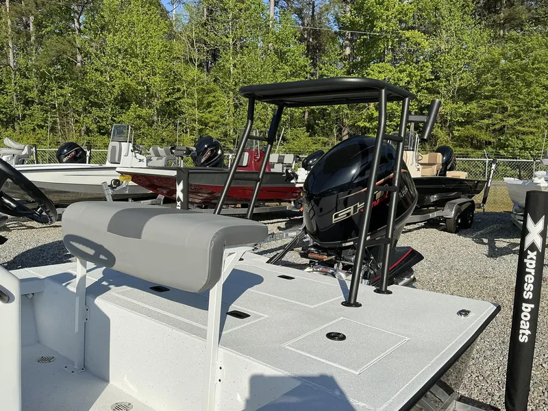 Slide: The Image of 2025 Xpress Skiff 185 boat with outboard motor, parked outdoors among trees. - 5