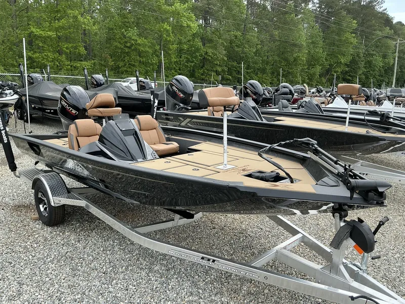 Slide: The Image of 2025 Xpress Hyper-Lift Bass Series boat on trailer, surrounded by trees and other boats. - 1
