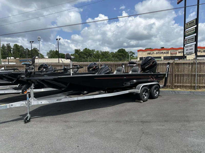 Slide: The Image of 2025 Xpress Hyper-Lift Bass Series boat on trailer under cloudy sky. - 1