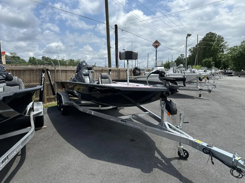 Slide: The Image of 2025 Xpress Hyper-Lift Bass Series boat on trailer, parked outdoors under cloudy sky. - 2