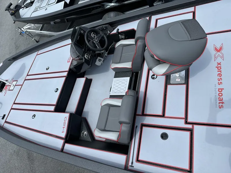 Slide: The Image of 2025 Xpress Hyper-Lift Bass Series boat interior with gray and red seating and steering console. - 6