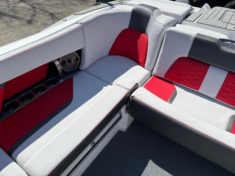 Slide: The Image of 2020 MasterCraft X24 boat interior with red and gray seating, cup holders, and speaker. - 11
