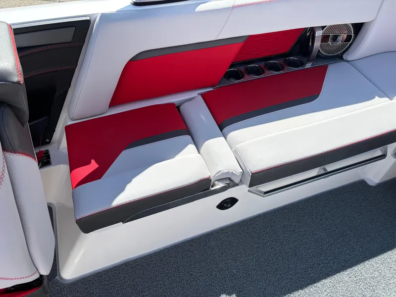 Slide: The Image of 2020 MasterCraft X24 boat interior with red and gray seating, cup holders, and speaker. - 13