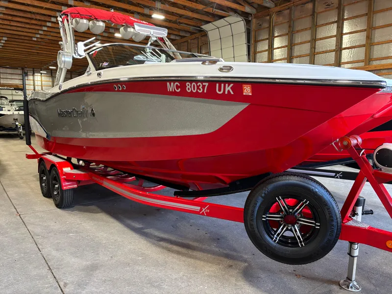 Slide: The Image of 2020 MasterCraft X24 boat in red and gray on a trailer inside a warehouse. - 18