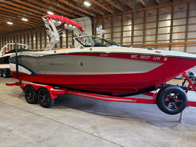 Slide: The Image of 2020 MasterCraft X24 boat in a warehouse, red and gray design on a trailer. - 20