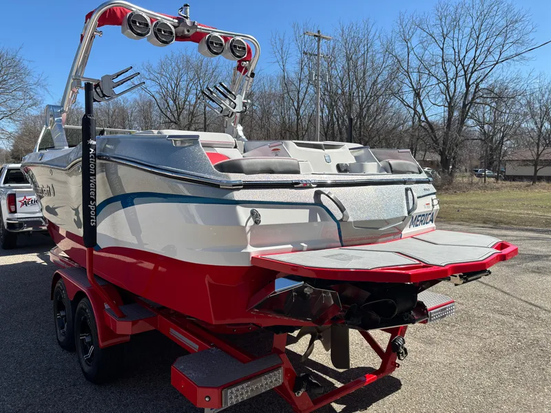 Slide: The Image of 2020 MasterCraft X24 boat with red accents and wakeboard tower, parked outdoors. - 4