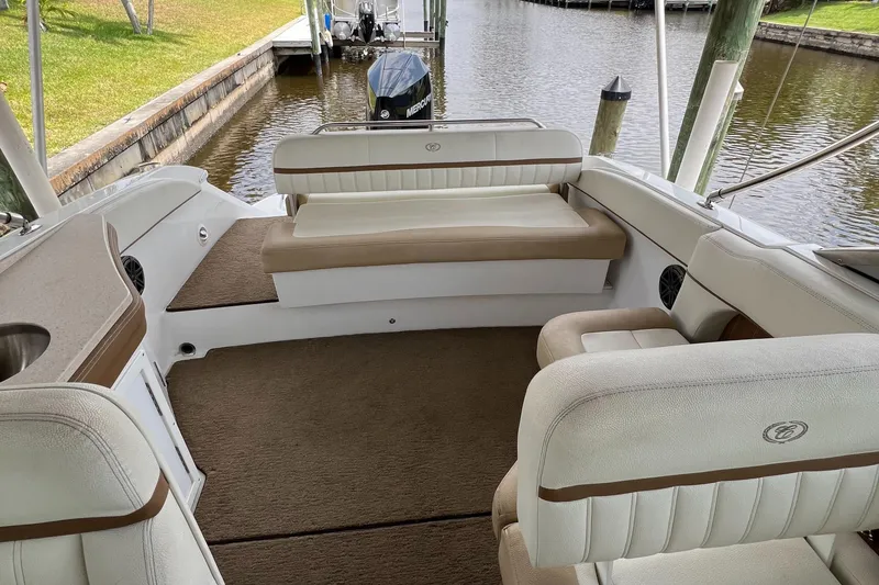 Slide: The Image of 2020 Cobalt 25SC boat interior with beige seating and carpeted floor by a dock. - 23