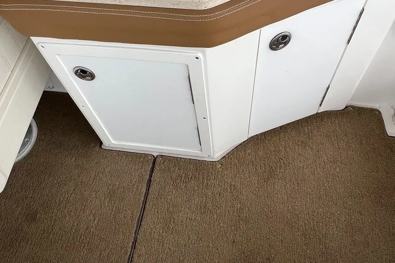 Slide: The Image of Interior view of a 2020 Cobalt 25SC boat, featuring carpeted flooring and storage compartments. - 24