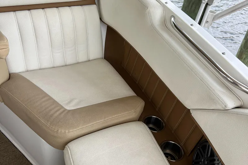 Slide: The Image of 2020 Cobalt 25SC boat interior with beige and white seating, cup holders, and speaker. - 25
