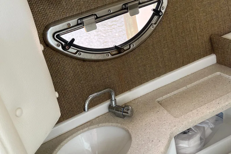 Slide: The Image of 2020 Cobalt 25SC boat interior with sink, faucet, and porthole window. - 28