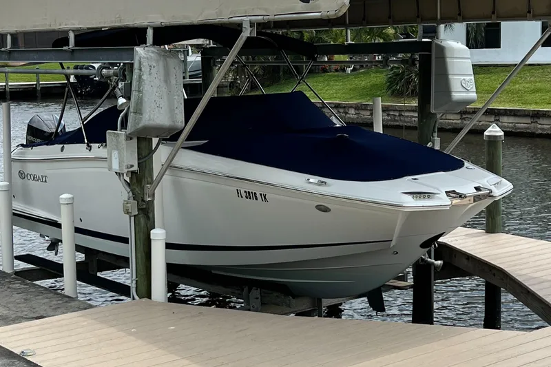 Slide: The Image of 2020 Cobalt 25SC boat docked with cover, in a marina setting. - 3