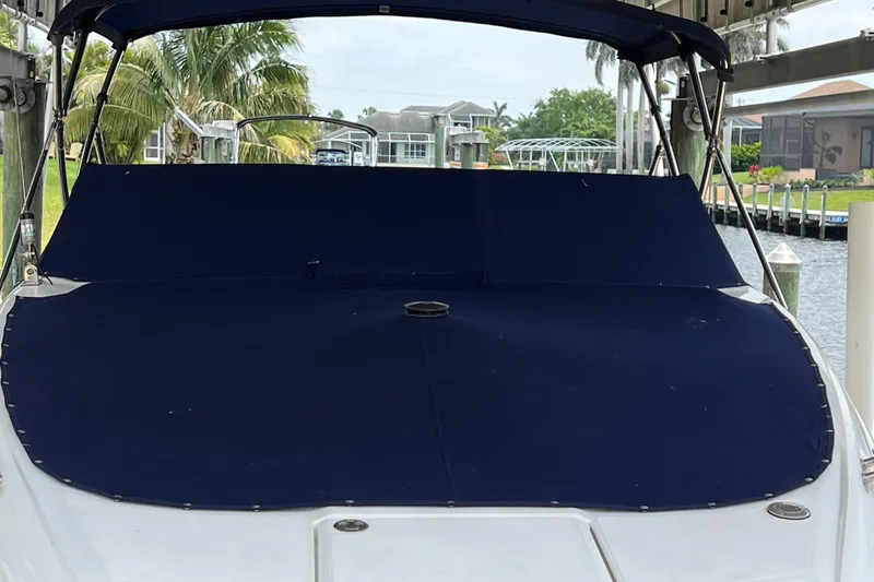 Slide: The Image of 2020 Cobalt 25SC boat with blue cover, docked near waterfront homes and palm trees. - 4