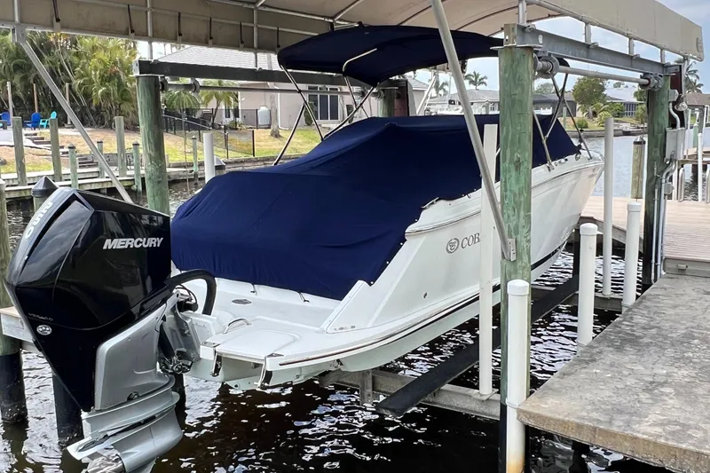Slide: The Image of 2020 Cobalt 25SC boat with Mercury engine, covered and docked at a marina. - 5