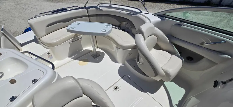 Slide: The Image of 2006 Chaparral Sunesta 254 boat interior with seating and table, featuring white upholstery. - 16