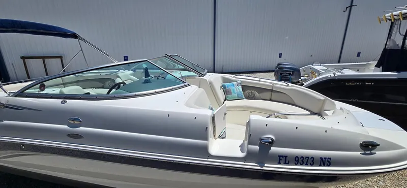 Slide: The Image of 2006 Chaparral Sunesta 254 boat with white exterior, docked near a warehouse. - 19
