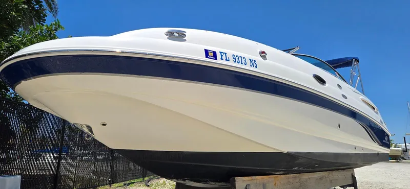 Slide: The Image of 2006 Chaparral Sunesta 254 boat on display, white and blue exterior, sunny day. - 21