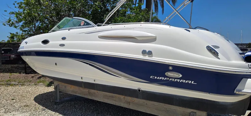 Slide: The Image of 2006 Chaparral Sunesta 254 boat with blue and white exterior, parked on gravel. - 24