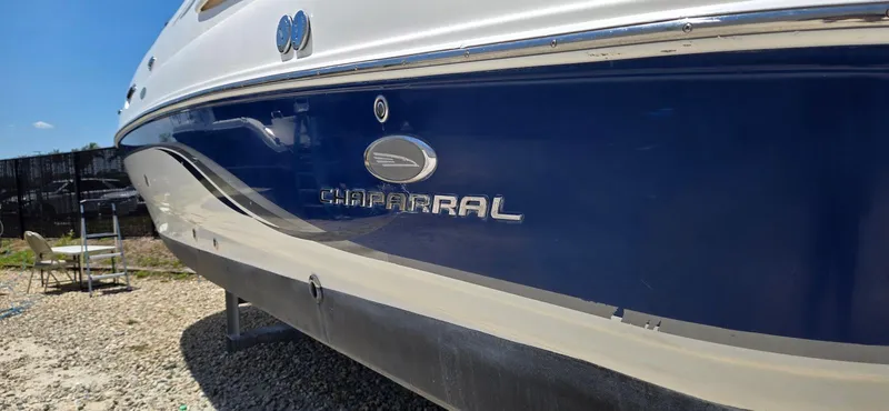 Slide: The Image of 2006 Chaparral Sunesta 254 boat, blue and white exterior, parked on gravel. - 25