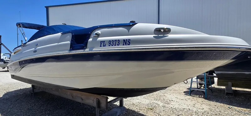 Slide: The Image of 2006 Chaparral Sunesta 254 boat on a trailer, white and blue exterior, parked outdoors. - 4