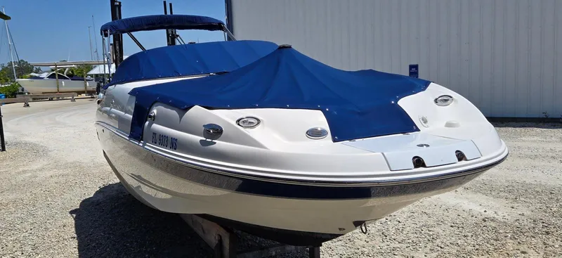 Slide: The Image of 2006 Chaparral Sunesta 254 boat with blue cover, parked on gravel near a building. - 5