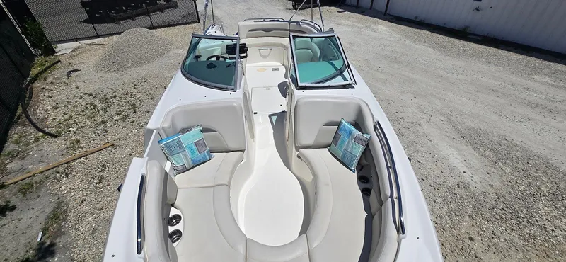 Slide: The Image of 2006 Chaparral Sunesta 254 boat interior with seating and cushions, parked on gravel. - 9